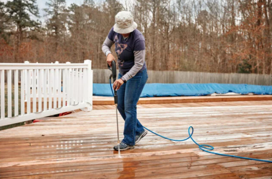 woman power washing deck